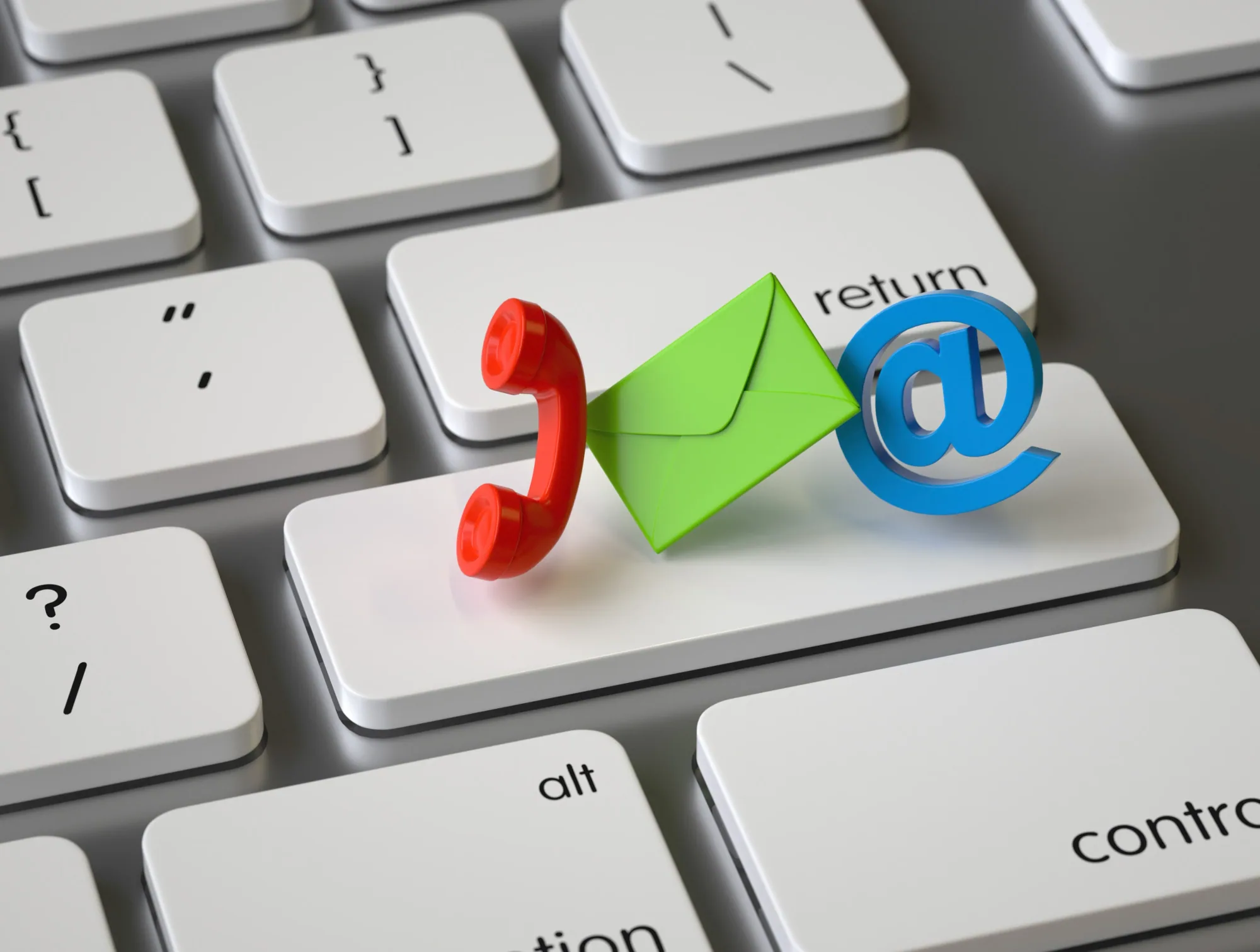 A close view of a keyboard return key with small telephone, envelope and at-sign symbols resting on it.
